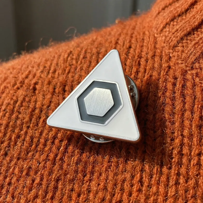 Enamel lapel pin of the A3Lab mark, macro shot on rust-colored wool